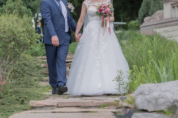 Noiva e noivo caminham juntos pela mão no parque — Fotografia de Stock