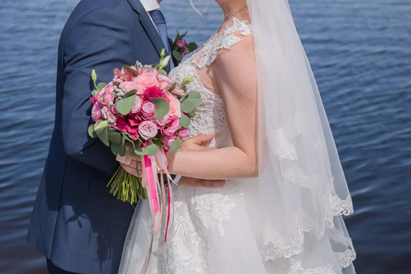 Bride and groom stand together against the water — Stock Photo, Image