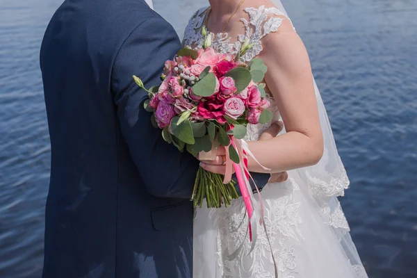 Bride and groom stand together against the water — Stock Photo, Image