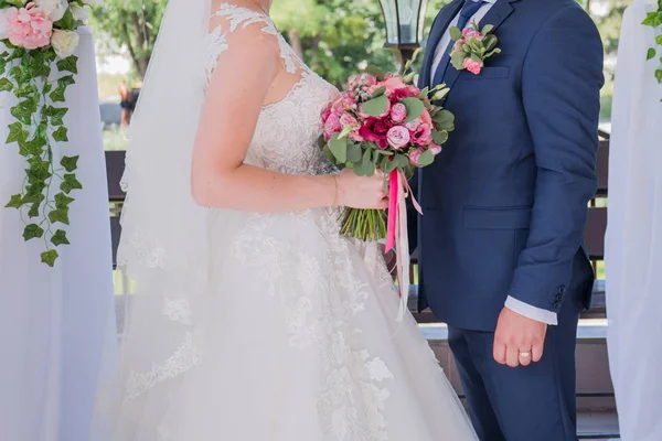 Bride and groom stand together under the arch of the wedding ceremony — Stock Photo, Image