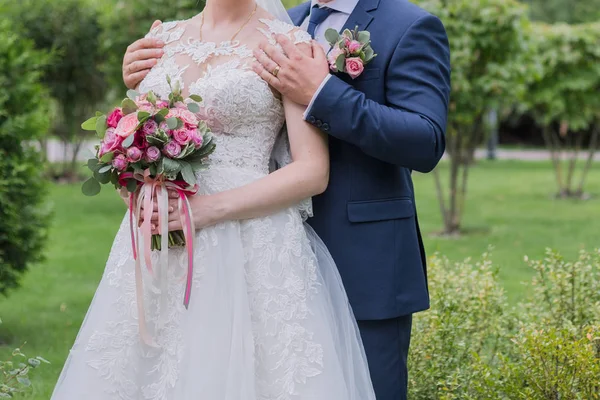 Bruden och brudgummen kramas i parken — Stockfoto