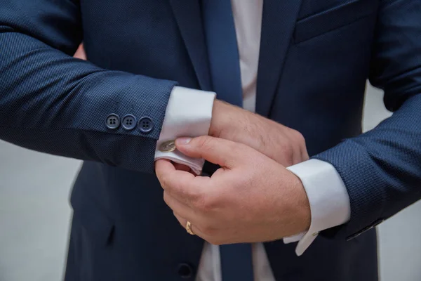 The groom fastens the cuffs of the sleeves on the shirt — Stock Photo, Image
