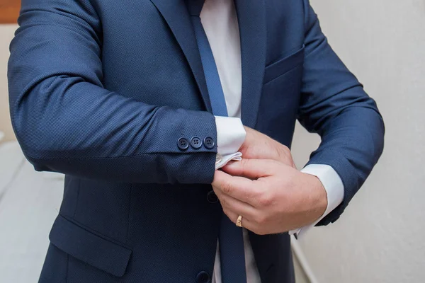 The groom fastens the cuffs of the sleeves on the shirt — Stock Photo, Image