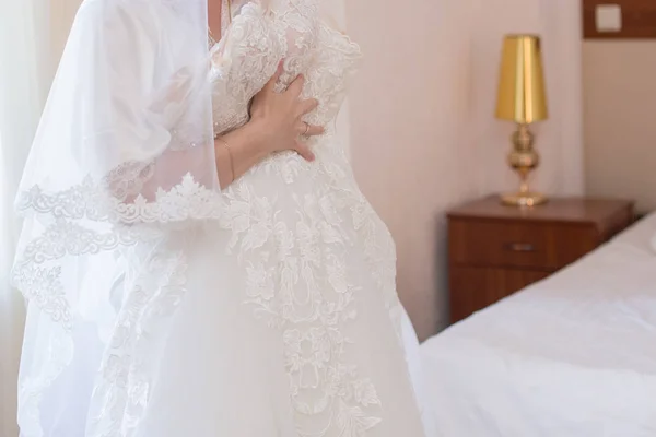 Noiva em vestido de vestir e vestido de noiva em mãos — Fotografia de Stock
