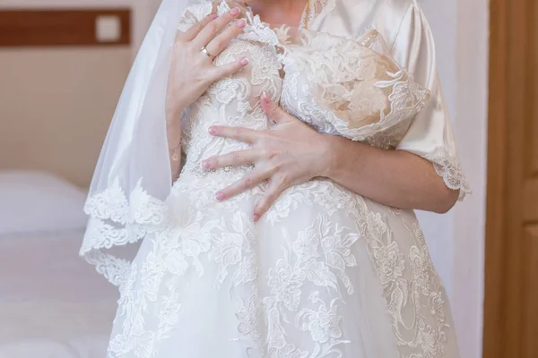 Noiva em vestido de vestir e vestido de noiva em mãos — Fotografia de Stock