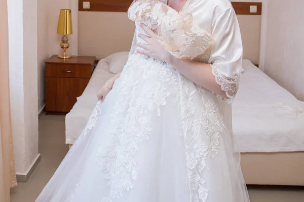 Bruid in badjas en trouwjurk in handen — Stockfoto