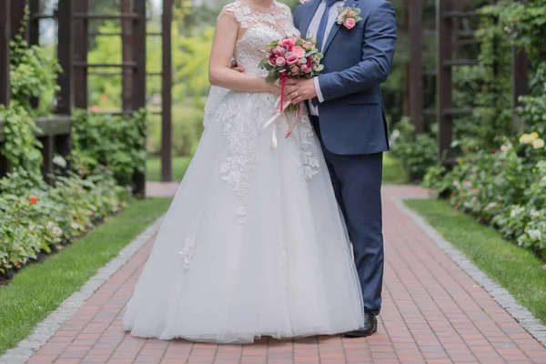 Bruid en bruidegom en bruiloft boeket in het park — Stockfoto