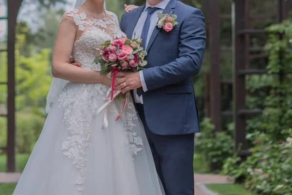 Nevěsta a ženich a svatební kytice v parku — Stock fotografie