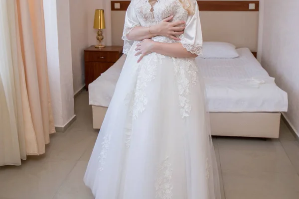 Bride in dressing gown holding wedding dress — Stock Photo, Image