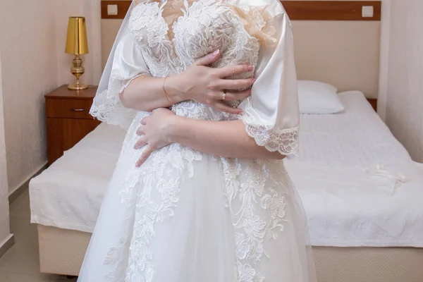 Bride in dressing gown holding wedding dress — Stock Photo, Image