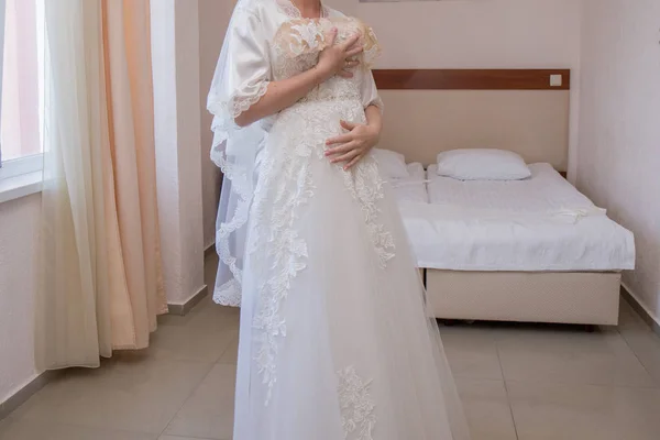 Novia en bata y vestido de novia en las manos — Foto de Stock