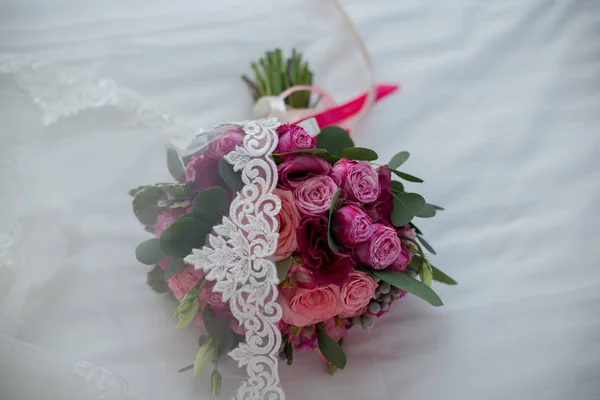 Wedding bridal bouquet with pink flowers lying on the bed — Stock Photo, Image