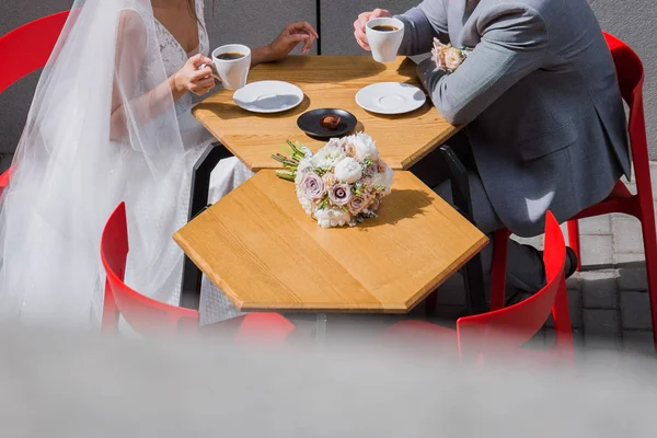 Gli sposi si siedono a un tavolo in un caffè bevendo caffè — Foto Stock