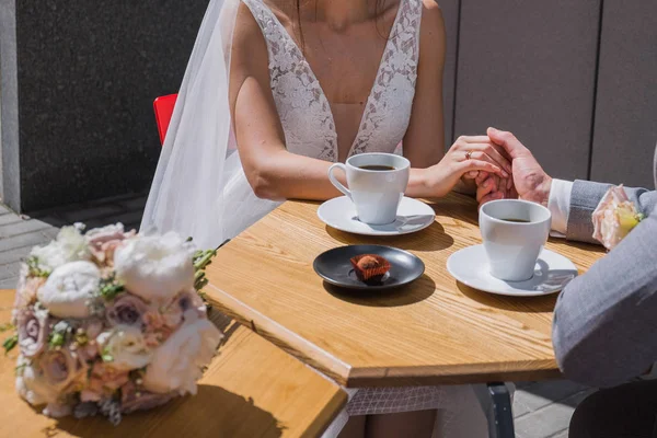 A noiva e o noivo sentam-se em uma mesa em um café que bebe o café — Fotografia de Stock