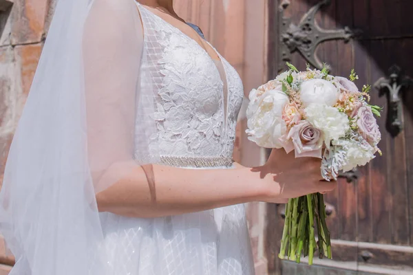 Mariée avec bouquet de mariage et voile près de l'église — Photo