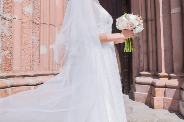 Brud med brudbukett och slöja nära kyrkan — Stockfoto