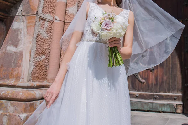 Sposa con bouquet da sposa e velo vicino alla chiesa — Foto Stock
