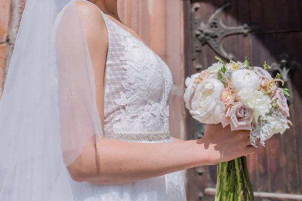 教会の近くで結婚式のブーケとベールを持つ花嫁 — ストック写真