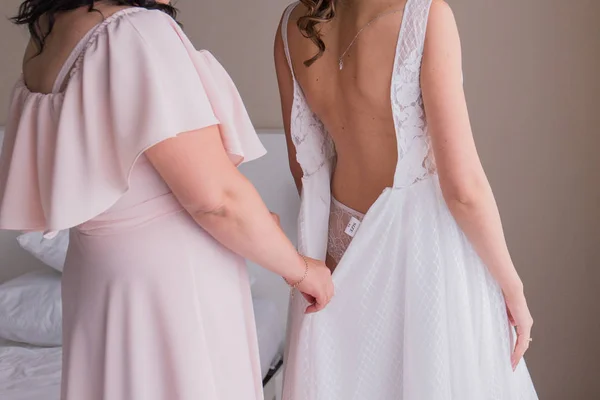 ピンクのドレスで花嫁介添人は、無重力ウェディングドレスを置きます — ストック写真
