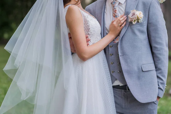 Braut und Bräutigam stehen zusammen in einer Umarmung im Park — Stockfoto