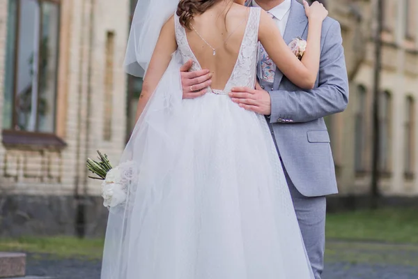Bruden och brudgummen står tillsammans i en omfamning i parken — Stockfoto