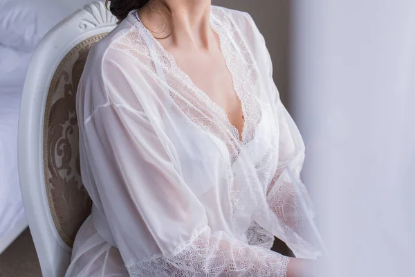 La sposa è seduta su una sedia indossando un peignoir — Foto Stock