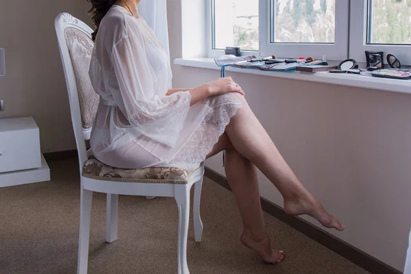 A noiva está sentada em uma cadeira usando um peignoir — Fotografia de Stock