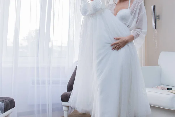 Sposa in peignoir in possesso di un abito da sposa — Foto Stock