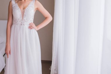 bir gelinlik içinde gelin pencerenin yakınında duruyor