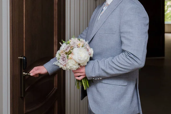 The groom opens the door with a bouquet in their hands — Stock Photo, Image