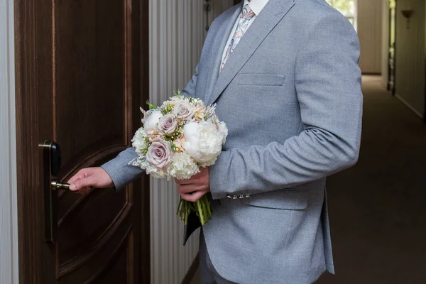 The groom opens the door with a bouquet in their hands — Stock Photo, Image