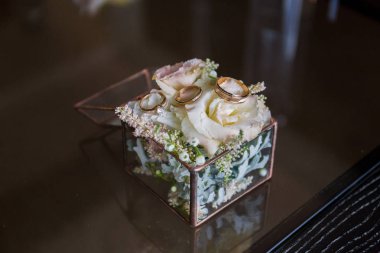 Altın halkalar ve çiçekler ile cam kutu