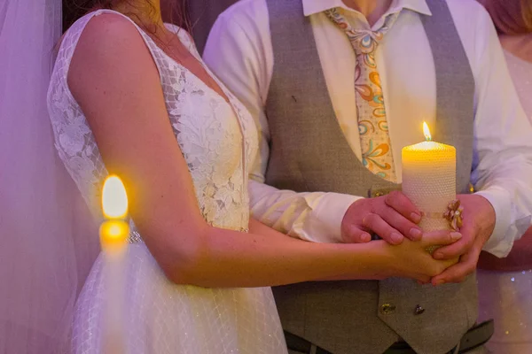 Menyasszony és a vőlegény egy gyertyát tartani a kezükben együtt — Stock Fotó