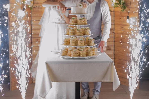 Невеста и жених разрезают свадебный торт и фейерверк — стоковое фото