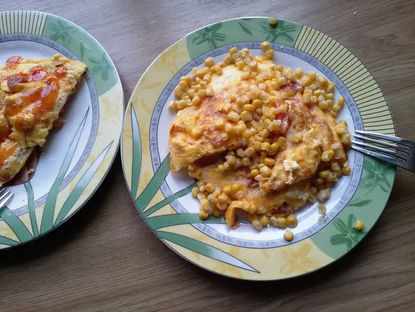 Omelete com milho em pratos na mesa — Fotografia de Stock