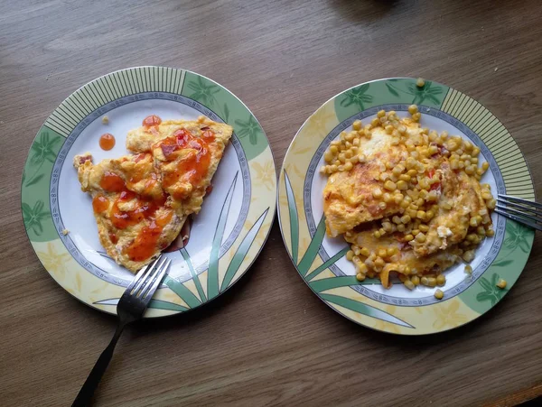 Omelete com milho em pratos na mesa — Fotografia de Stock