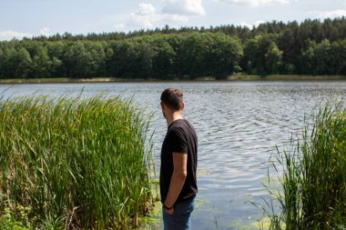 Ormandaki gölün yanında bir adam.