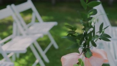 Düğün töreni için dekorlu beyaz sandalyeler.