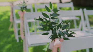 Düğün töreni için dekorlu beyaz sandalyeler.