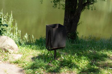 Parkta demir bir çöp tenekesi.