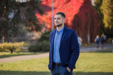 Sonbaharda parkta takım elbiseli bir adam.