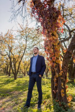 Sonbaharda parkta takım elbiseli bir adam.