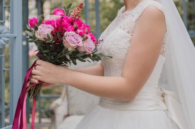 Gelin, gelinlik içinde bir buket tutuyor.