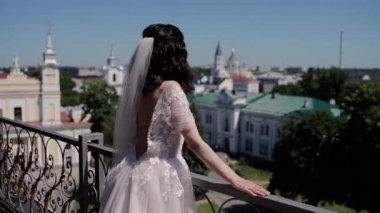 Gelin balkonda şehre bakıyor.