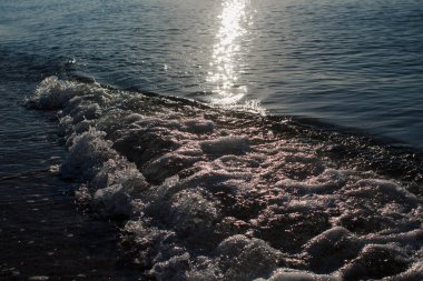 Sabah güneşi denizin üzerinde ve kumlu sahilde