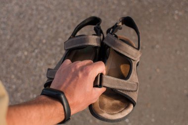 Kumsaldaki adamın elinde sandaletler