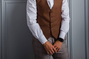 Papyonlu ve yelekli bir adam odada.