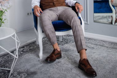 Takım elbiseli adam stüdyoda sandalyede oturuyor.