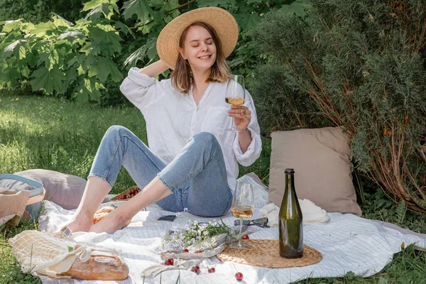 Piknikte hasır şapkalı bir kadın elinde bir bardak şarap tutuyor. Yaz dönemi maceraları