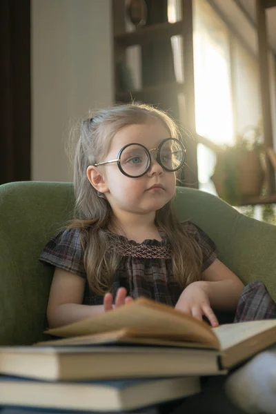 Egy aranyos kislány szemüvegben, aki könyveket olvas. Vissza az iskolába. — Stock Fotó